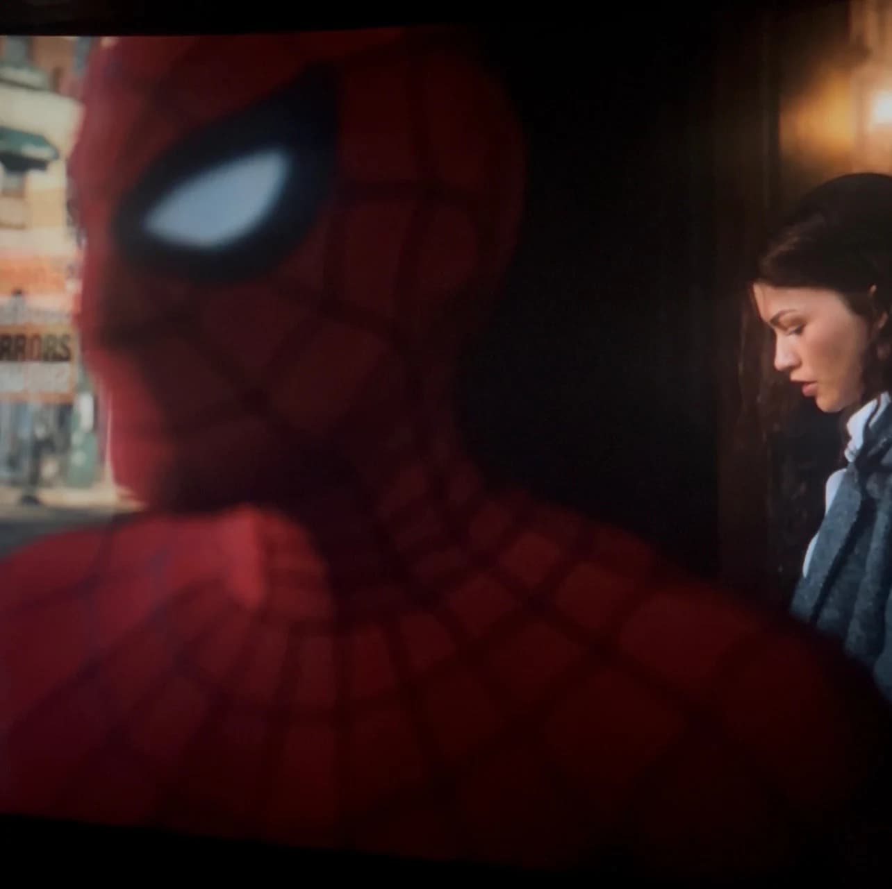 Spider-Man in the foreground looking toward MJ by a softly lit window