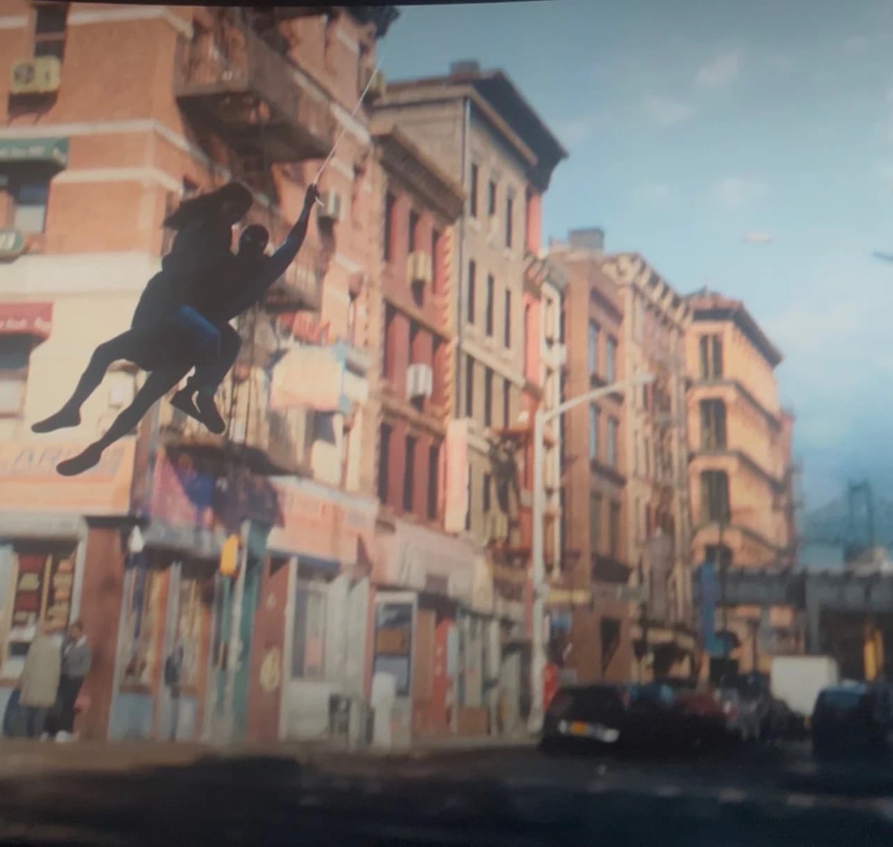 Spider-Man carrying a person while swinging above a sunlit New York street